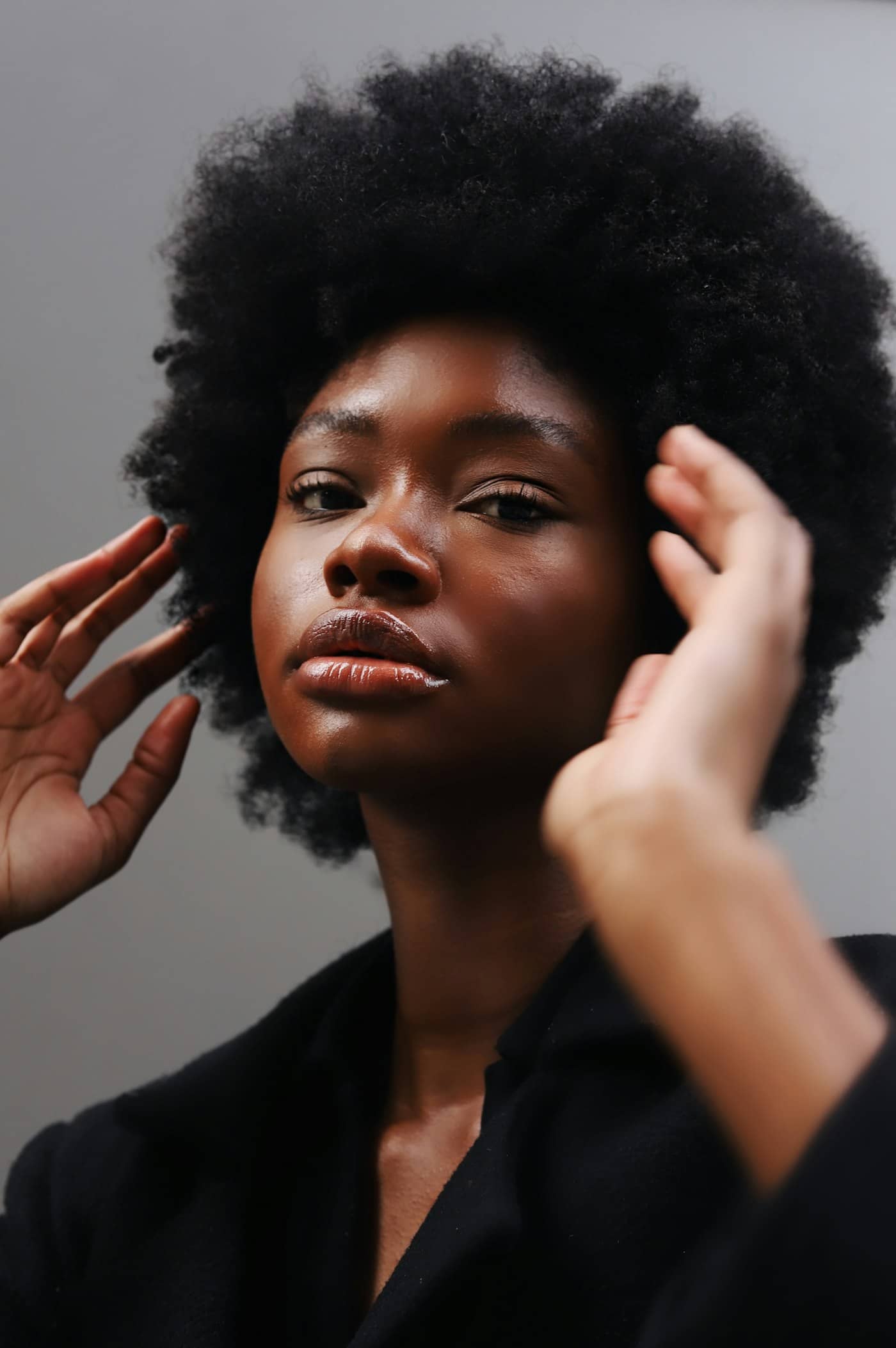 Femme aux cheveux afro, les mains dans les cheveux